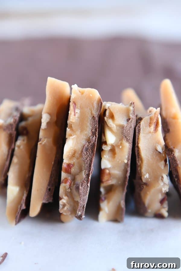 Seven pieces of perfectly golden homemade toffee arranged side-by-side on parchment paper.