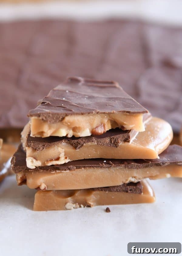 Four pieces of homemade toffee stacked on white parchment paper.