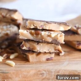 Four pieces of homemade toffee stacked on a wooden cutting board.