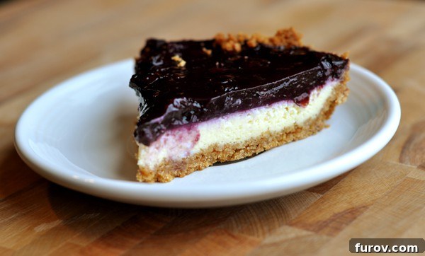 A pristine slice of blueberry cheesecake pie on a white plate, ready for serving.