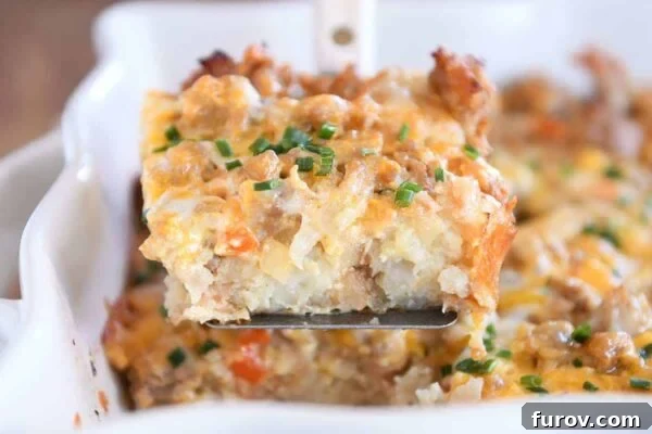 A delectable square of golden-brown tater tot breakfast casserole, perfectly scooped onto a metal spatula, ready to be served.