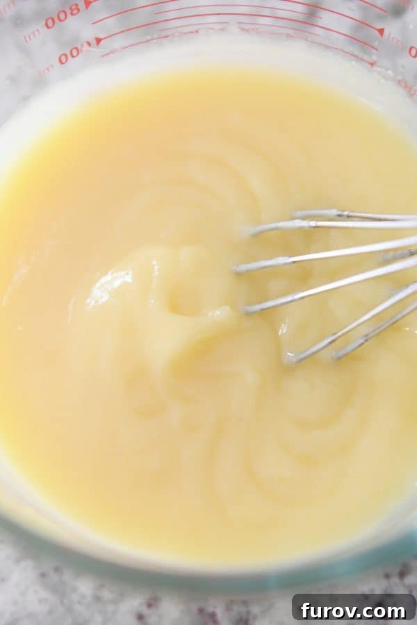 Bright and Zesty Instant Pot Lemon Curd 7 A close-up of beautifully smooth, vibrant Instant Pot lemon curd being whisked in a glass bowl, showcasing its rich, creamy texture.