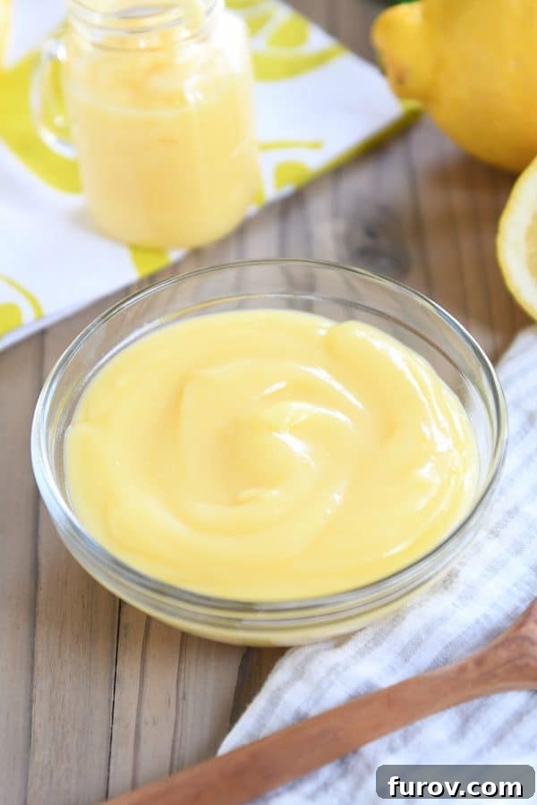 Bright and Zesty Instant Pot Lemon Curd 8 A charming glass bowl overflowing with smooth, vibrant lemon curd, presented on a striped linen napkin.