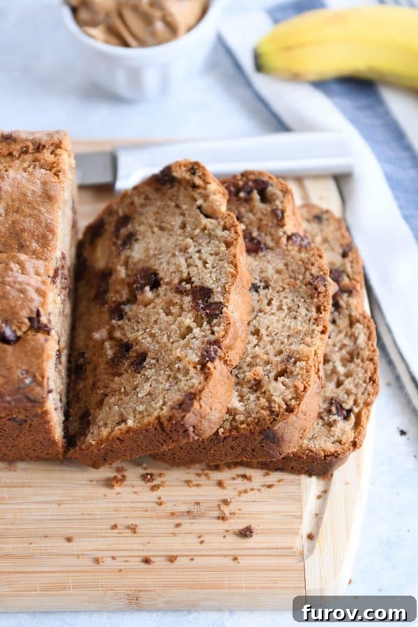 Slices from loaf of peanut butter banana bread on wood cutting board.