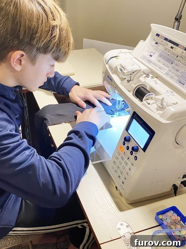 A focused teenage boy sits at a sewing machine, diligently working on black fabric, highlighting the effort and learning involved in making homemade gifts.