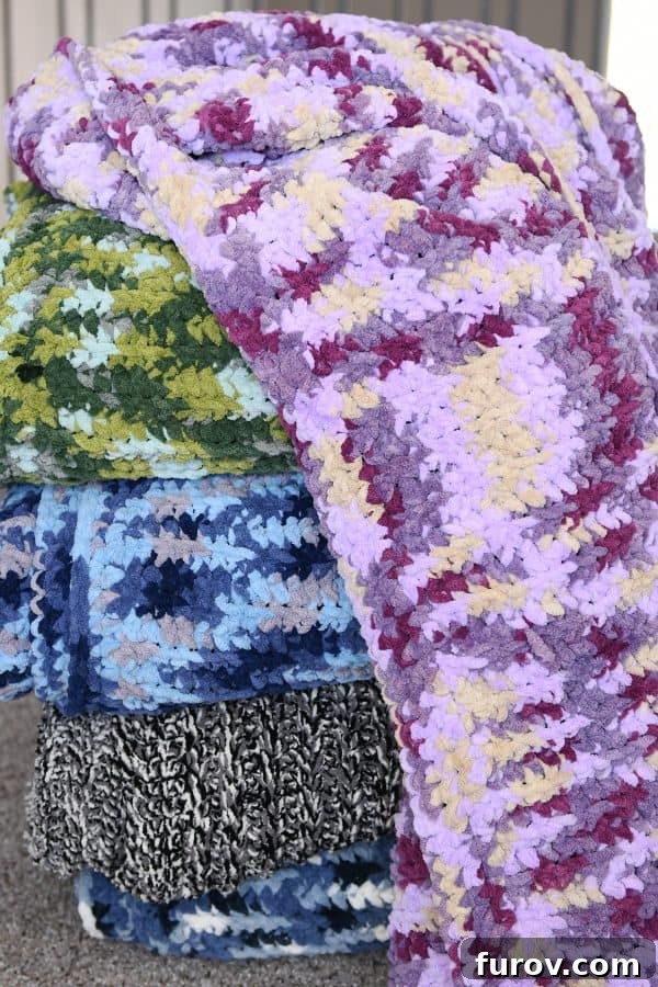 A neatly folded stack of various colored, soft crocheted blankets, symbolizing cozy comfort and handmade warmth.