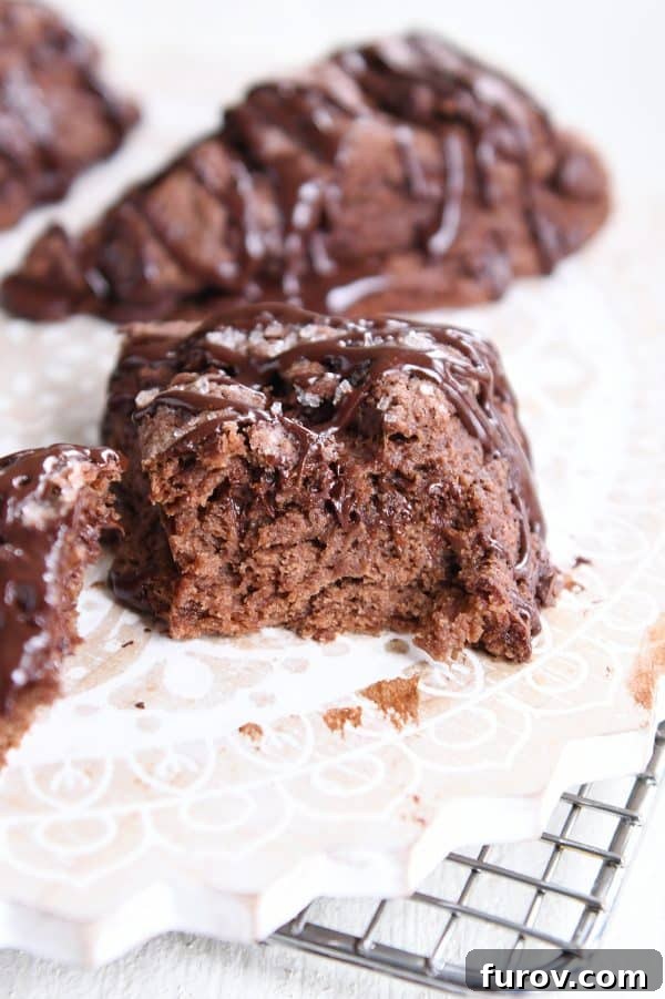A halved triple chocolate scone on a white platter, showing the interior with melted chocolate.