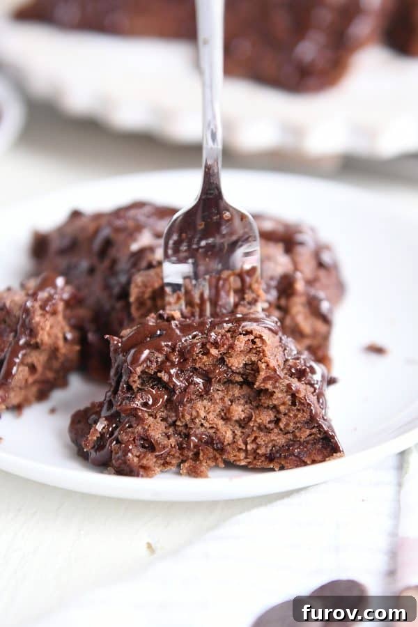 A fork scooping a piece from a chocolate scone on a white plate, showing the flaky texture.