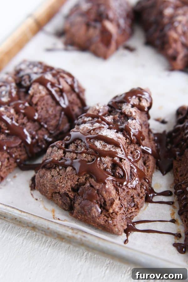 A single glazed chocolate scone resting on a sheet pan.