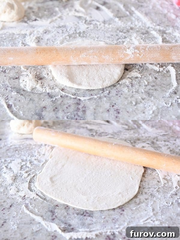 Someone rolling out a piece of flatbread dough on a floured counter using a wooden rolling pin.