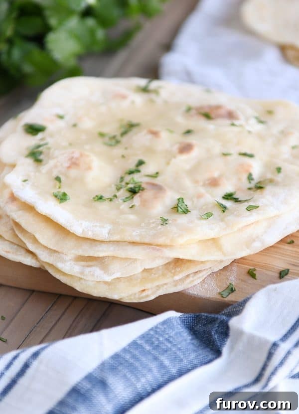 Stack of perfectly cooked yogurt flatbreads on a wooden cutting board, ready to serve.