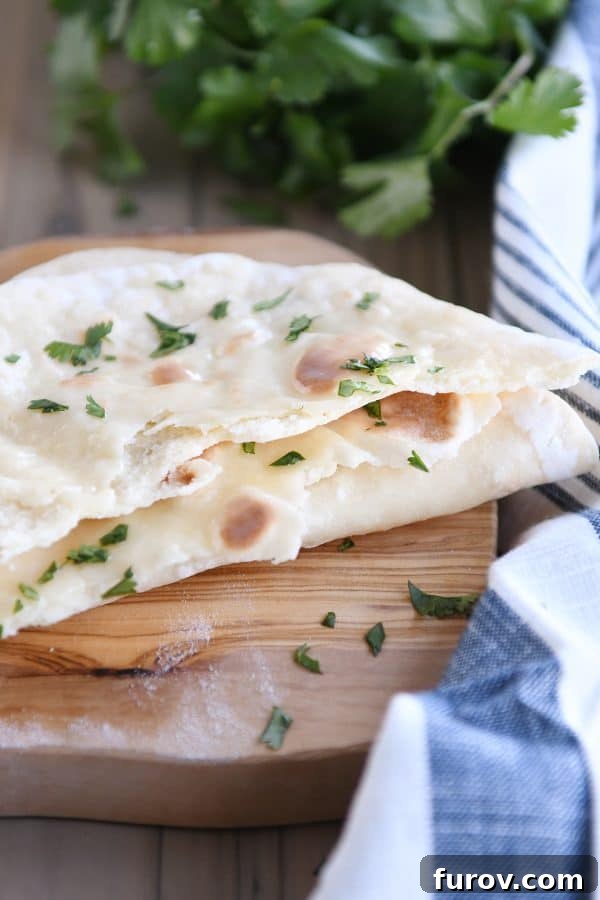 Yogurt flatbread torn in half on a wooden cutting board, revealing its soft and airy interior.