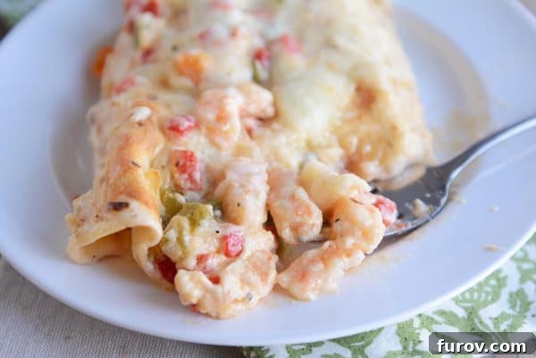 Velvet Shrimp Enchiladas Blanco 4 A close-up shot of a shrimp enchilada, showing off its creamy interior and vibrant ingredients, mid-bite.