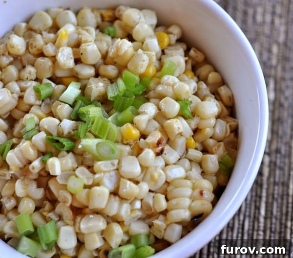 White bowl with grilled corn kernels and chopped green onions, showcasing a vibrant and fresh appearance.