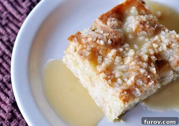 Close-up of a square piece of Rhubarb Streusel Cake, showcasing the golden streusel topping, soft cake layers, and generous drizzle of warm vanilla sauce.