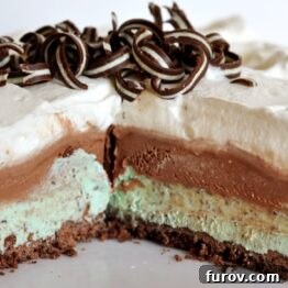 A vibrant green and brown slice of Grasshopper Ice Cream Pie on a white plate with chocolate shavings.