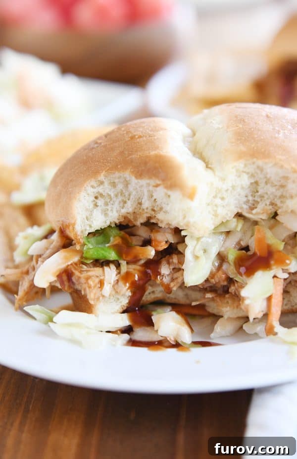 A delicious BBQ pulled pork sandwich with a bite taken out, showcasing the tender meat and sauce.