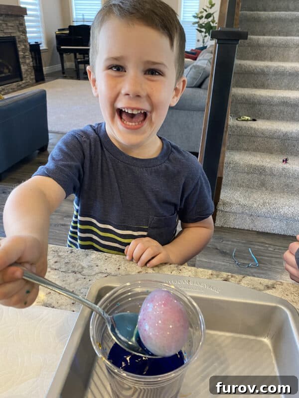 A young boy intently dyeing an Easter egg, focused on the task