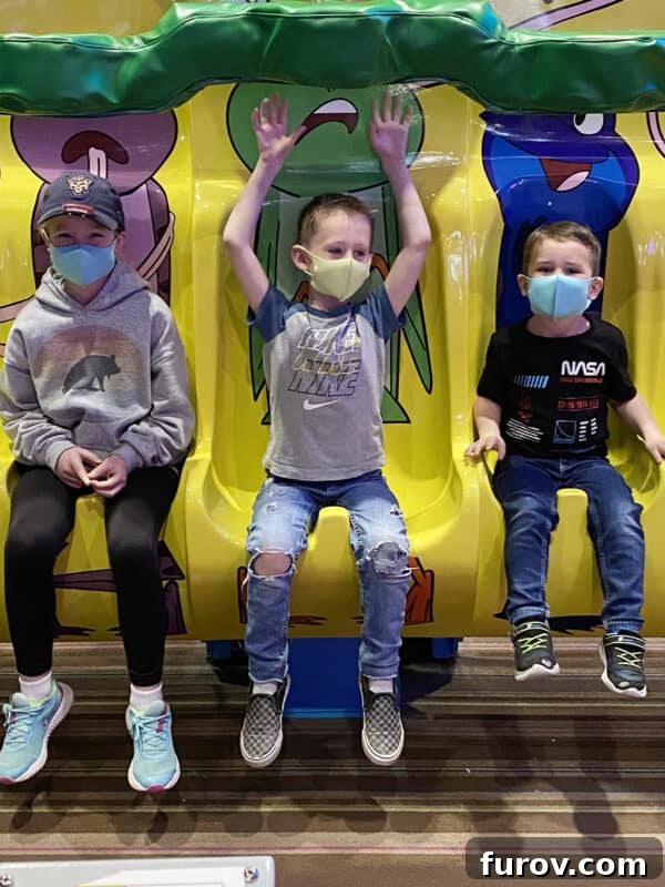 Three children joyfully riding an amusement park ride, experiencing a fun diversion