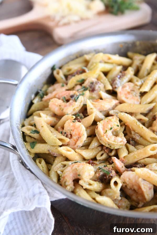 Vibrant Pesto Shrimp Pasta with Sun Kissed Tomatoes 2 Easy shrimp pesto pasta in skillet, garnished with fresh herbs.