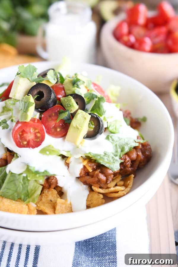 Elevated Taco Bowls with Zesty Creamy Lime Dressing Stovetop or Slow Cooker 2 Vibrant Floating Taco Bowls featuring seasoned meat, rice, fresh lettuce, juicy tomatoes, and sliced olives, all drizzled with creamy lime dressing, served in white bowls.