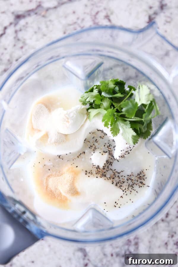 Elevated Taco Bowls with Zesty Creamy Lime Dressing Stovetop or Slow Cooker 7 A blender filled with fresh cilantro, black pepper, garlic powder, softened cream cheese, and buttermilk, ready to be blended into a creamy lime dressing.