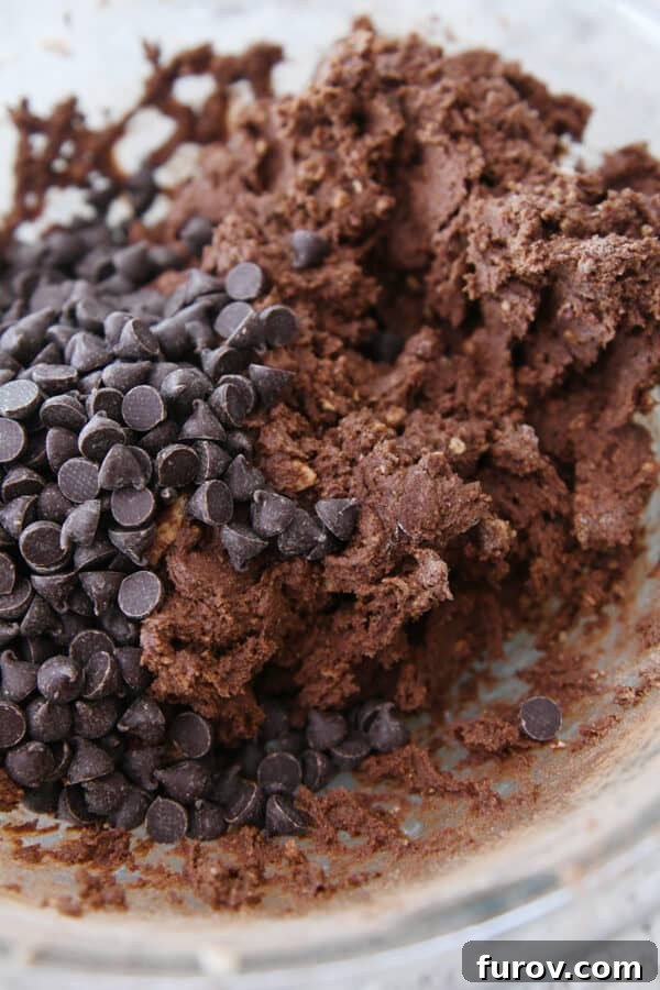 Chocolate cookie dough with chocolate chips in glass bowl.