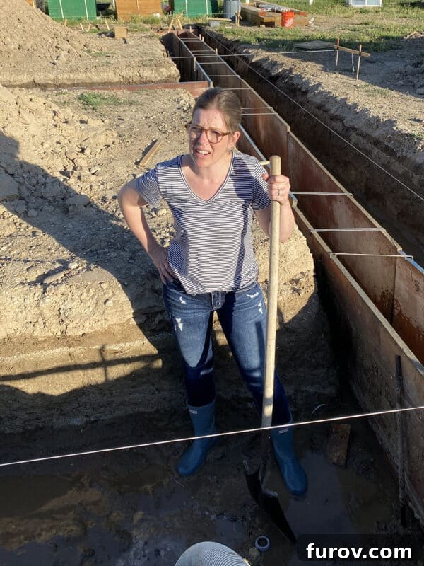 woman standing in a mud-filled trench with a shovel, representing overcoming personal challenges and hard work