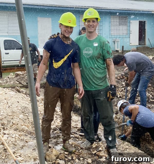 father and son in hard hats standing in the rain, symbolizing dedication to humanitarian work and facing challenges together