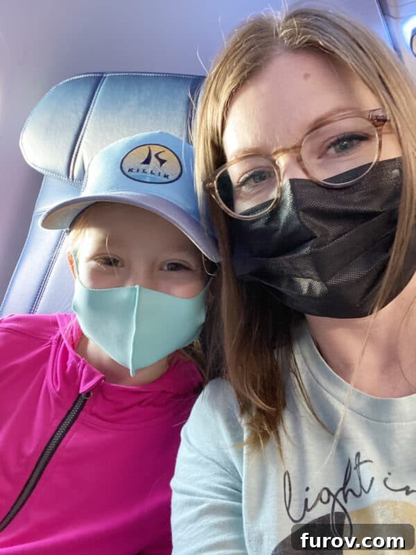 mother and daughter on a plane with masks, symbolizing safe and exciting travel adventures