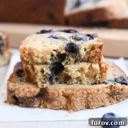 loaf of blueberry muffin bread split in half on top of full slice of bread