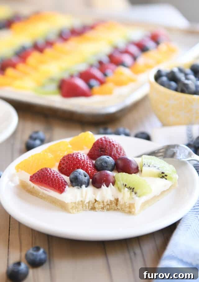 Square of the best fruit pizza with bite taken out on white plate.