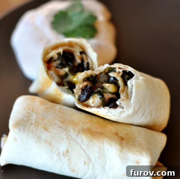 An egg roll split in half on top of another cooked egg roll, showcasing the rich filling.