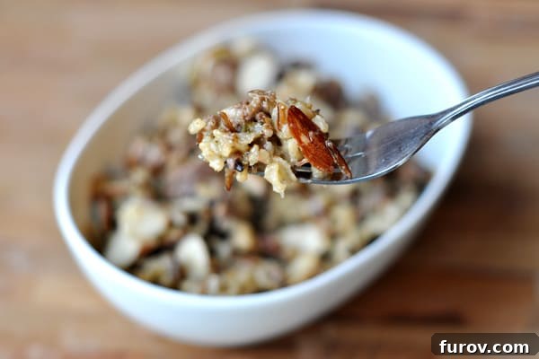 A serving of Wild Rice Hot Dish in a white bowl, with a fork taking a bite, showcasing the tender rice and savory mix.