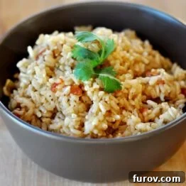 A close-up shot of the Baked Brown Spanish Rice, showing individual grains, flecks of tomato, and spices, with a vibrant and inviting texture.
