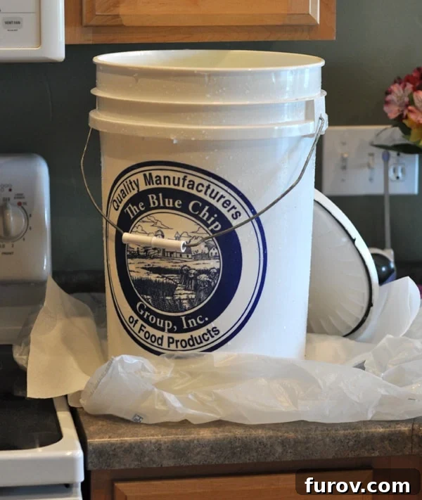 white five gallon bucket on a countertop with the lid next to it