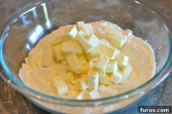 cubed butter on flour in a glass bowl, ready for blending.
