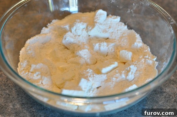 butter cubes tossed with flour in a glass bowl, coating lightly.