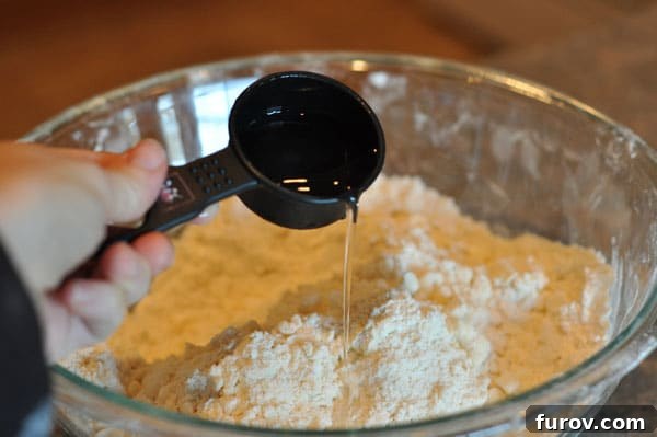 measuring cup adding water to a flour and butter mixture, careful drizzling.