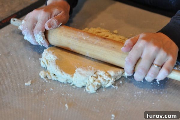 pie dough starting to be rolled out, with a rolling pin in motion.