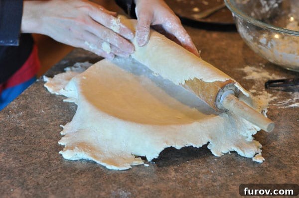 unrolling a pie crust over a pie dish, careful placement.