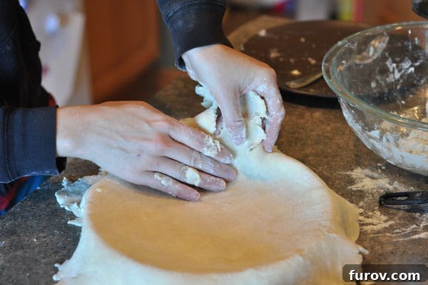 a pie crust being lifted into a pie dish, easing into place.
