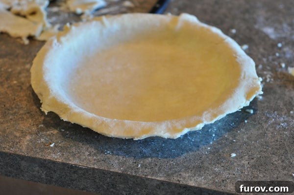 pie crust with trimmed edges in pie plate, ready for the next layer.