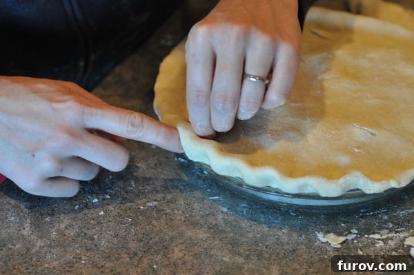 pie crust getting edges fluted, creating a decorative border.