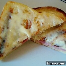 A freshly prepared Croque Monsieur sandwich cut in half, revealing melted cheese and ham layers.