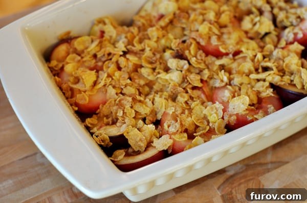 White casserole dish filled with golden-brown roasted fruit and a crunchy streusel topping, fresh out of the oven.