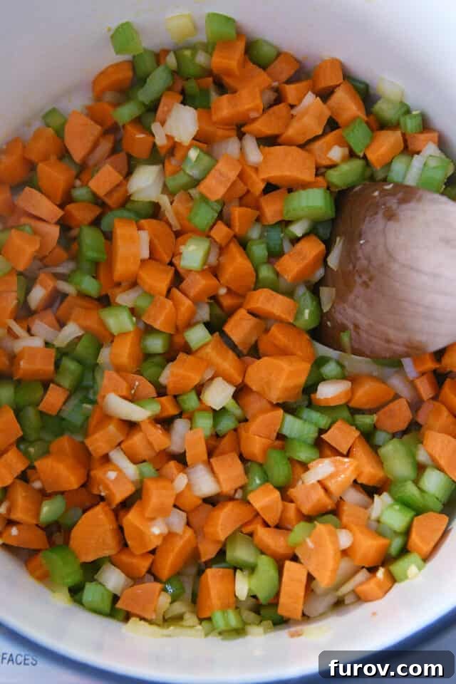 Sunshine Lemon Chicken Orzo Soup 3 Freshly diced carrots, onions, and celery being sautéed in a cast iron pot, forming the aromatic base for the soup.
