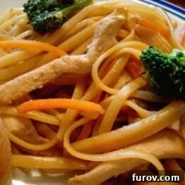 Close-up of a bowl of Easy Chicken Lo Mein, garnished with fresh herbs and sesame seeds.