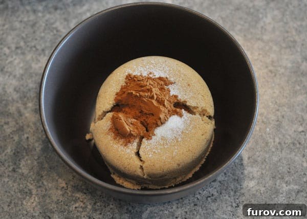 A small black bowl filled with a mixture of rich brown sugar and aromatic cinnamon, ready to be combined.