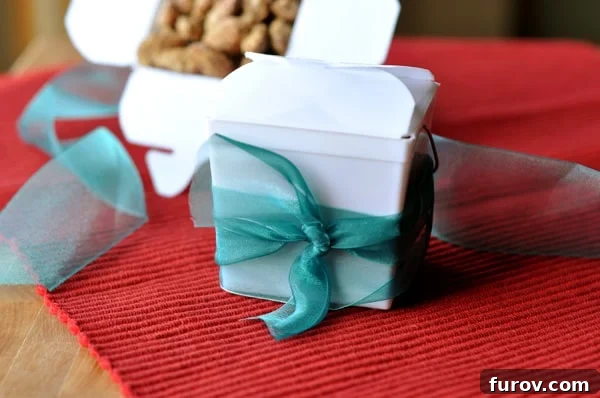 Charming white takeout containers, elegantly tied with blue ribbons, filled to the brim with homemade candied almonds, ready for gifting.